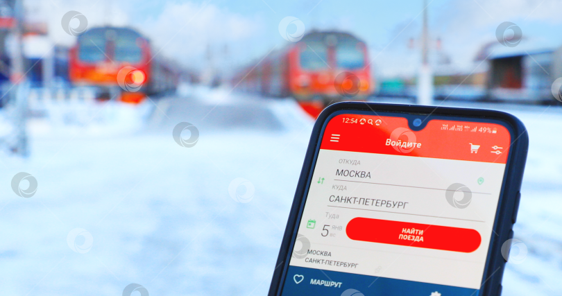 Скачать Поиск билетов через приложение РЖД в смартфоне на фоне электричек. Калуга 2025 фотосток Ozero