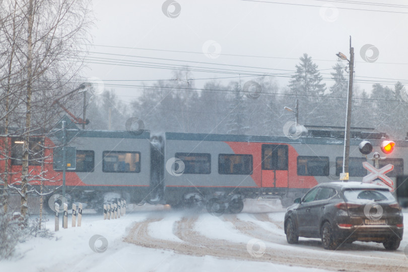 Скачать Россия, Гатчина, январь 2025 года: Автомобили стоят на железнодорожном переезде в снежный зимний день фотосток Ozero