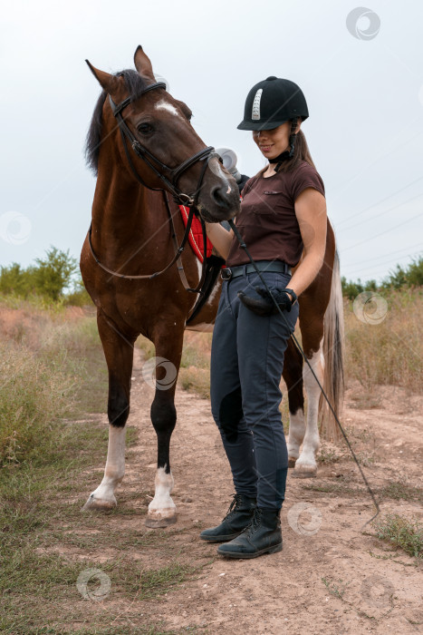 Скачать Девушка стоит на полевой дороге и держит под уздцы свою пегую лошадь фотосток Ozero
