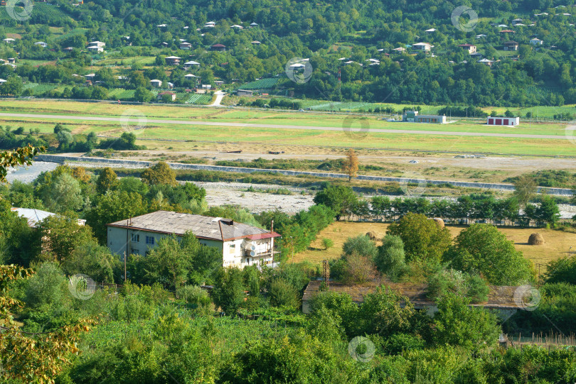 Скачать Грузинский горный пейзаж с проселочной дорогой, видом на деревню на берегу горной реки фотосток Ozero