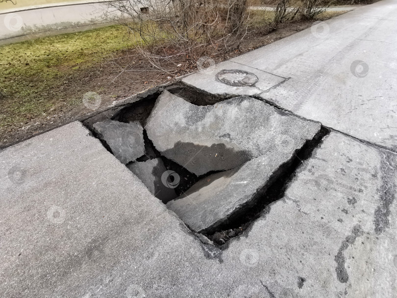 Скачать Большая дорожная выбоина в городской черте представляет опасность для транспортных средств и пешеходов, вид крупным планом фотосток Ozero