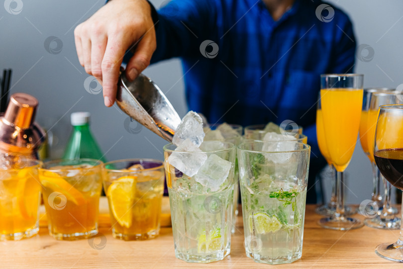 Скачать Бармен готовит коктейль с лаймом, апельсином, лимоном и льдом фотосток Ozero