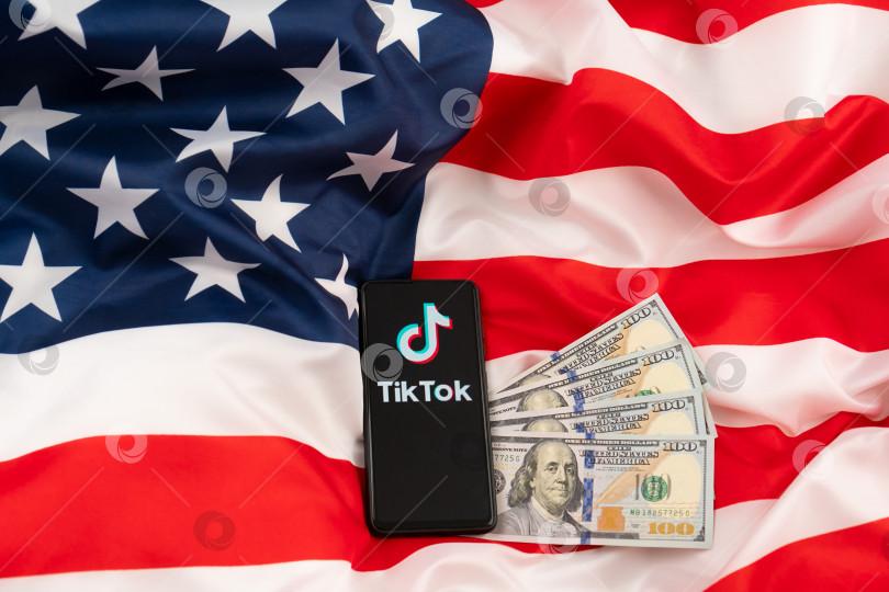 Скачать Логотип Tiktok на смартфоне и доллары США. Концепция запрета Tik tok, предложенная Дональдом Трампом. Россия, Казань - 08 августа 2020 г. фотосток Ozero