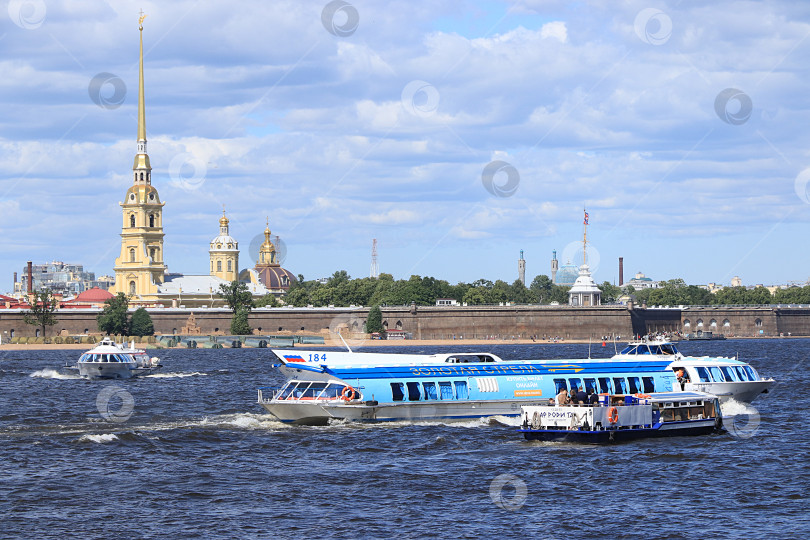 Скачать Россия, Петербург, 29 июня 2019 года. Стрелка Васильевского острова. На фотографии изображена Петропавловская крепость на берегу Невы на фоне неба и прогулочный катер с туристами, любующимися видами города. фотосток Ozero