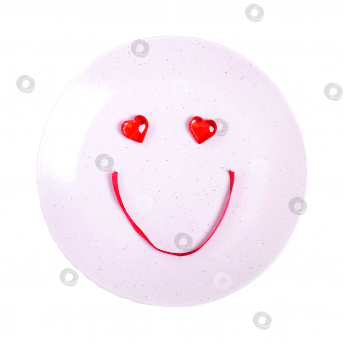 Скачать Милое улыбающееся личико из декоративных сердечек и красной ленты на тарелке фотосток Ozero