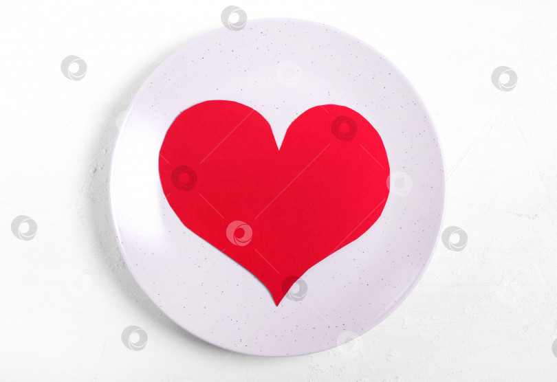 Скачать Красное картонное сердечко на керамической тарелке на белом столе. фотосток Ozero