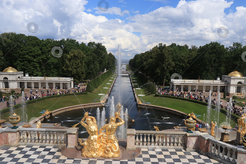 Скачать Россия, Санкт-Петербург, Петергоф, 8 июля 2019 года. На фото: фонтан Большого каскада в Нижнем парке Государственного музея-заповедника "Петергоф" и люди, которые прогуливаются по парку и любуются архитектурой. фотосток Ozero