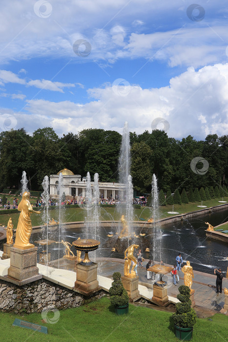 Скачать Россия, Санкт-Петербург, Петергоф, 4 июля 2018 года. На фото фонтан "Большой каскад" в Верхнем парке Государственного музея-заповедника "Петергоф" и люди, прогуливающиеся по парку фотосток Ozero