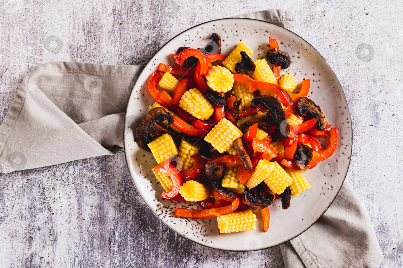 Скачать Аппетитный салат из консервированной кукурузы, жареных грибов и перца крупным планом на тарелке, вид сверху фотосток Ozero