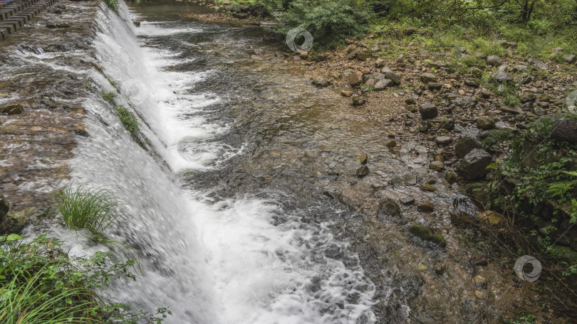 Скачать Потоки воды стекают с уступа в русло реки, пенясь фотосток Ozero