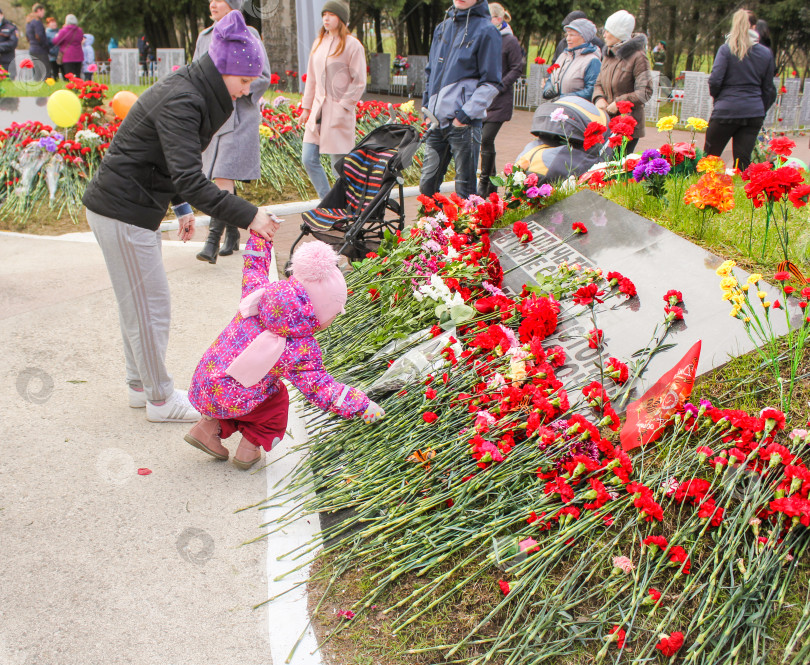 Скачать Ребенок кладет цветы к мемориальной плите. фотосток Ozero