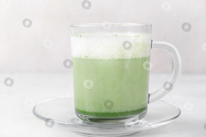 Скачать Матча латте с пенкой на растительном молоке в стеклянном стакане на белом столе. фотосток Ozero