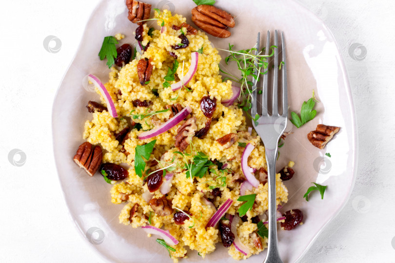 Скачать Салат с кускусом, сушеной клюквой, орехами пекан, красным луком, микрозеленью и апельсиновой заправкой на керамической тарелке. фотосток Ozero