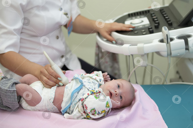 Скачать Врач делает ультразвуковое исследование новорожденному ребенку.Медицинское обследование ребенка с помощью ультразвукового оборудования фотосток Ozero