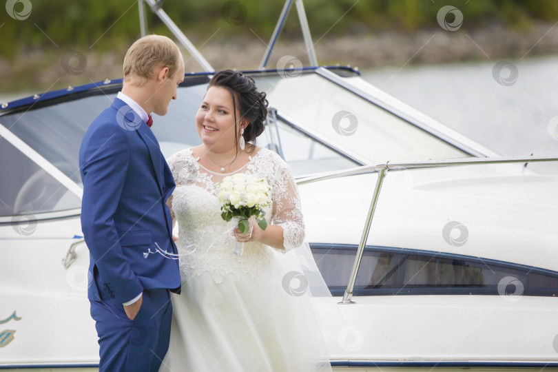 Скачать Толстые жених и невеста стоят возле яхты и разговаривают друг с другом. фотосток Ozero