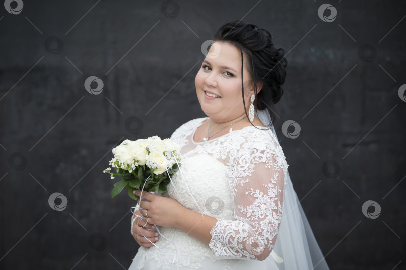 Скачать Красивая толстая невеста позирует с букетом цветов на темном фоне. фотосток Ozero