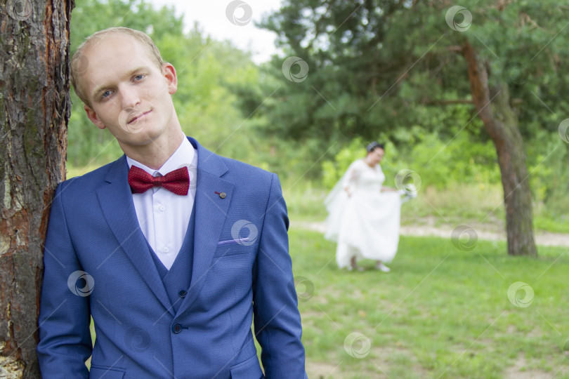 Скачать Грустный жених европейской внешности и невеста размыты на заднем плане. фотосток Ozero