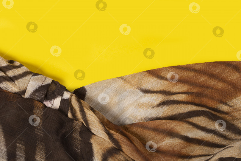 Скачать Ткань с принтом в виде тигровых полос крупным планом. Рисунок на ткани в виде тигровой шкуры на желтом фоне. фотосток Ozero