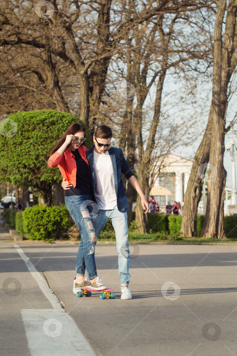 Скачать Мужчина учит подругу кататься на скейтборде фотосток Ozero