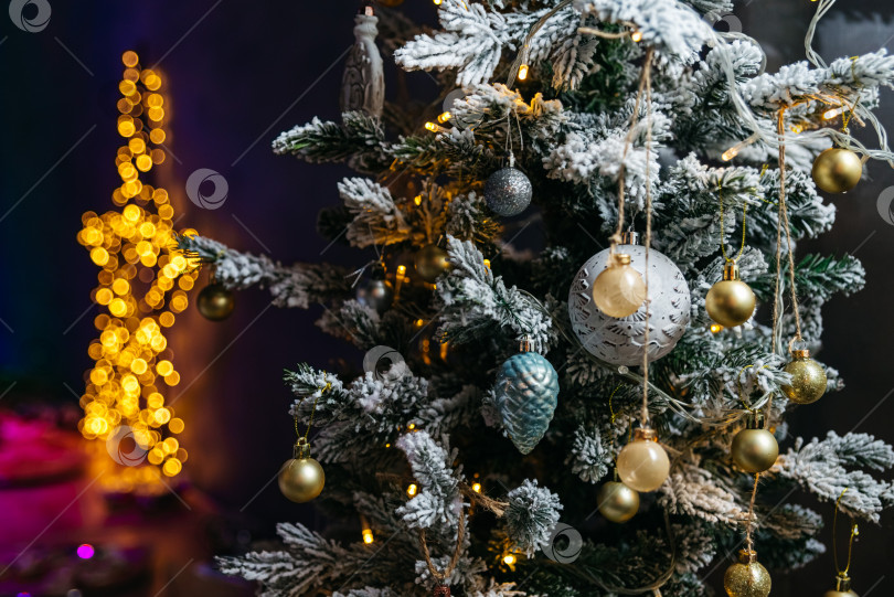 Скачать Рождественская елка, украшенная игрушками и гирляндами на темном фоне. Размытые огни в форме звезды на заднем плане. фотосток Ozero