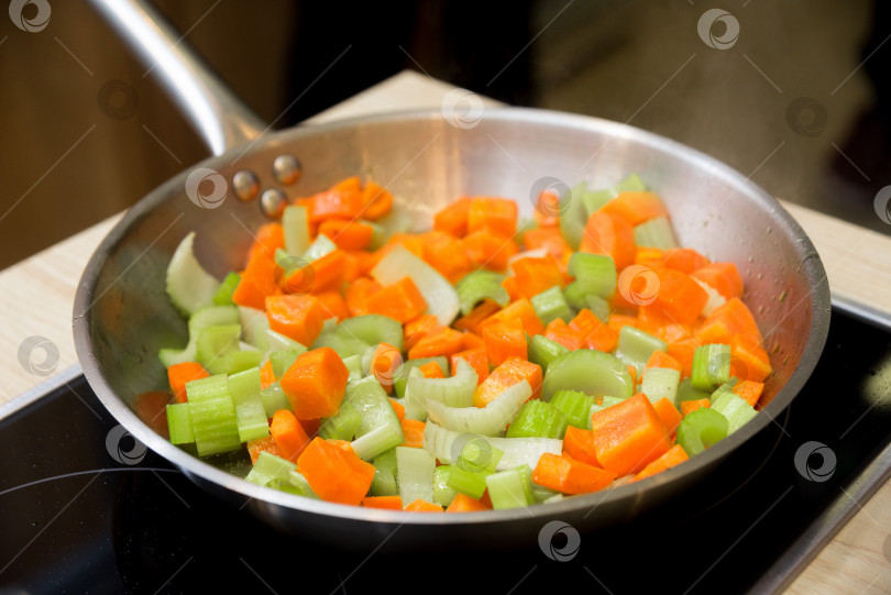 Скачать Нарезанные сельдерей и морковь обжарить на сковороде на плите фотосток Ozero
