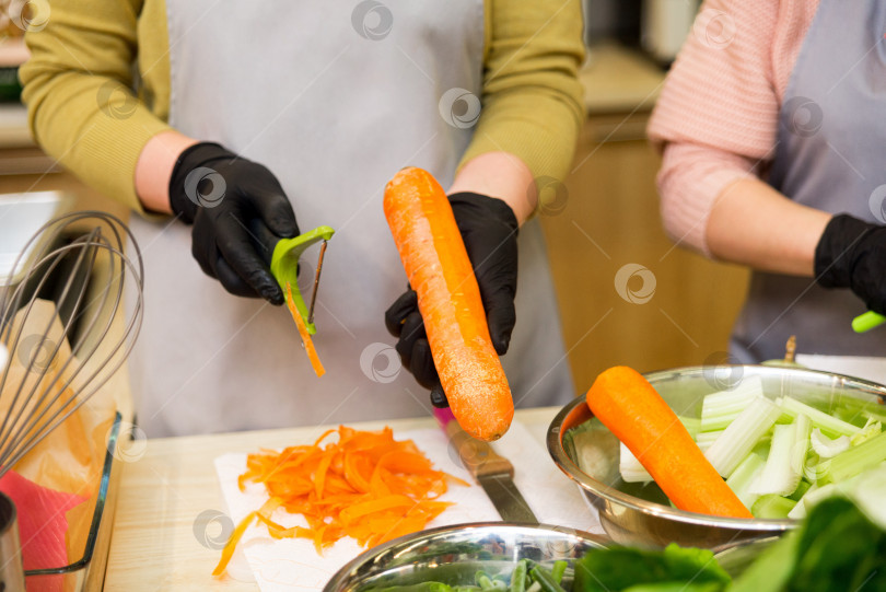 Скачать женские руки держат овощечистку и чистят морковь фотосток Ozero