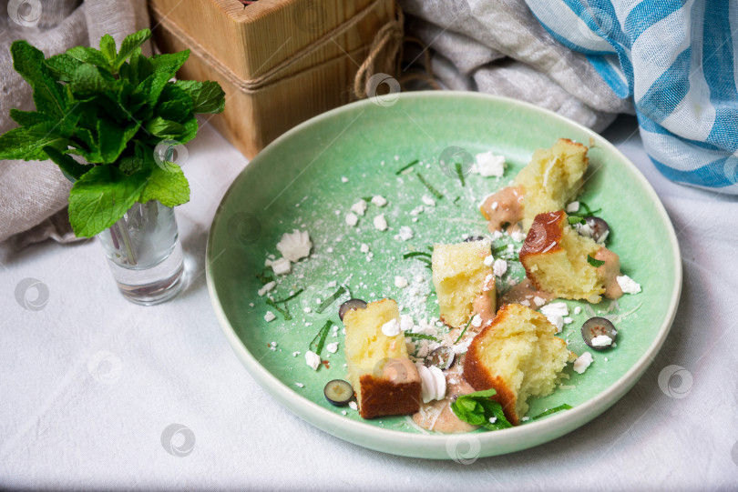 Скачать Кусочки бисквита с сахарной пудрой и нарезанными листиками мяты в зеленой тарелке на столе фотосток Ozero