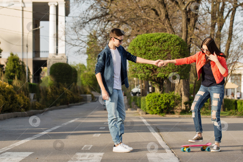 Скачать Мужчина учит подругу кататься на скейтборде фотосток Ozero
