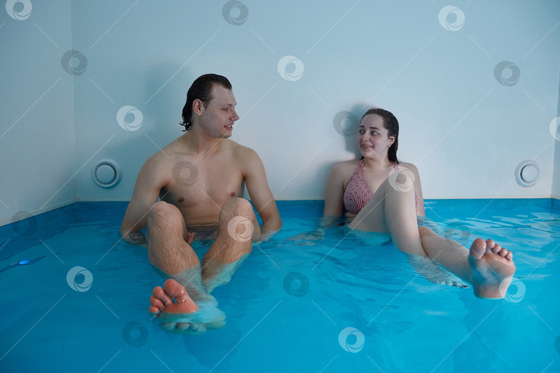 Скачать Мужчина и женщина сидят в бассейне в воде с морской солью. Плавающая концепция. фотосток Ozero
