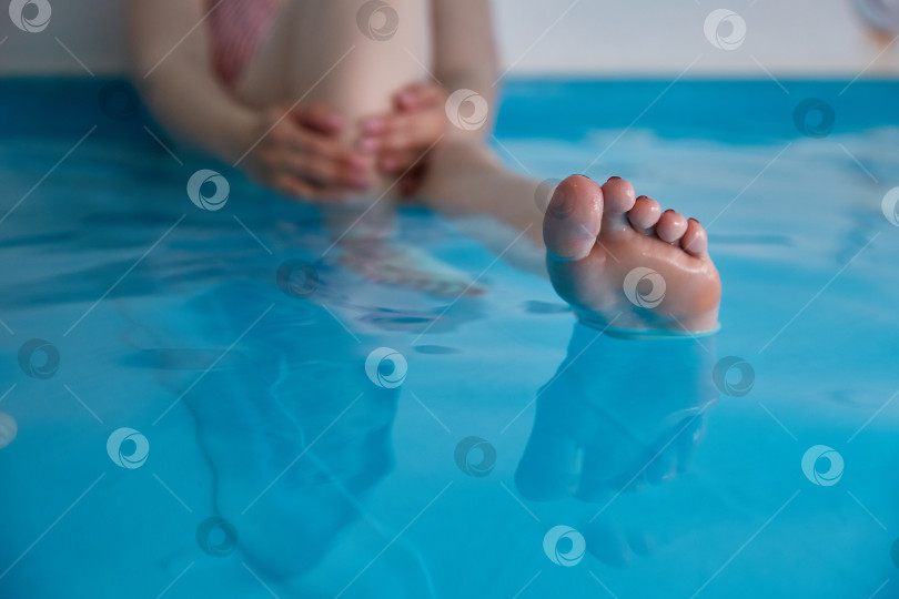 Скачать Женские ножки в бассейне с морской водой. Водные спа-процедуры в санатории. фотосток Ozero