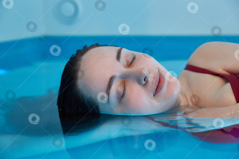 Скачать Расслабленная молодая женщина в воде. Закройте глаза и расслабьтесь фотосток Ozero