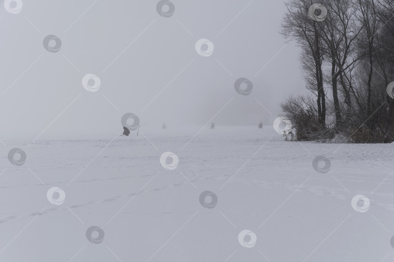 Скачать Зимняя рыбалка - рыбаки сидят на льду в густом тумане. фотосток Ozero