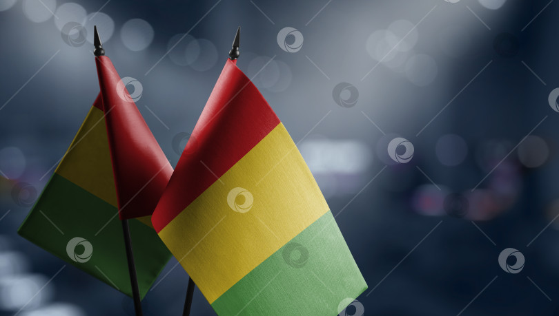 Скачать Small flags of the Guinea on an abstract blurry background фотосток Ozero