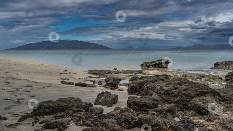 Скачать Отлив в океане. Обнаженные валуны морского дна на песчаном пляже. фотосток Ozero