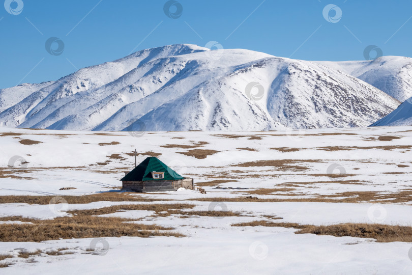 Скачать Уединенная горная хижина на замерзшем лугу. фотосток Ozero