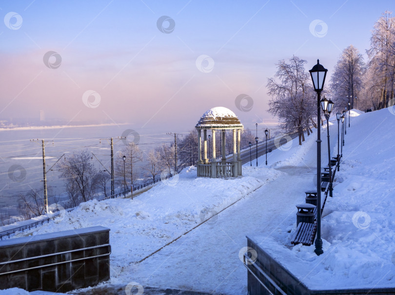 Скачать Перманент. Пермский край. Россия. 2025 год. Зимний солнечный морозный пейзаж реки Камы и городской набережной. Пешеходный маршрут, ведущий к городской набережной города Перми мимо ротонды. Россия. Зима 2025 года. фотосток Ozero