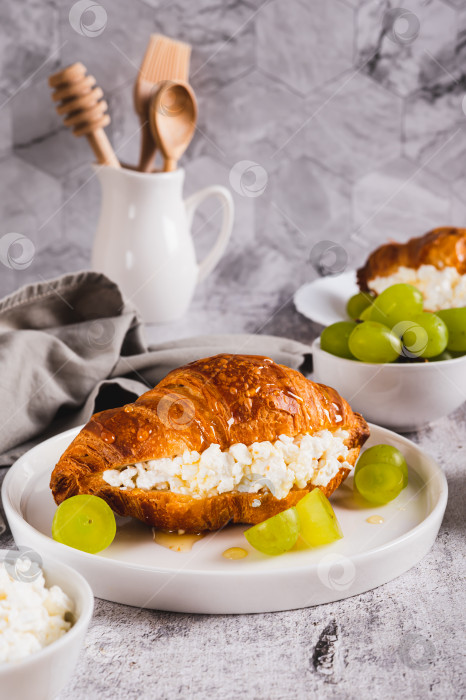 Скачать Вкусный круассан с творогом и виноградом на тарелке на столе, вид сверху фотосток Ozero