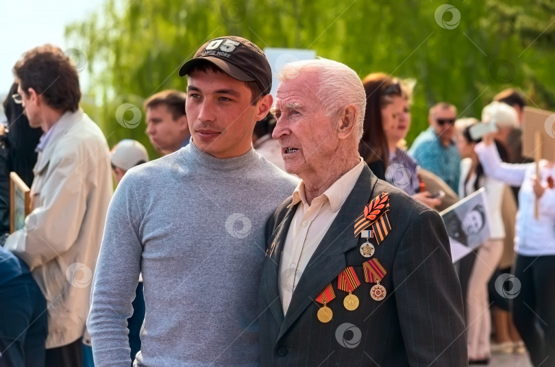 Скачать УЛЬЯНОВСК, РОССИЯ - 9 мая 2016 года: Молодой человек фотографируется с ветераном после участия в шествии "Бессмертного полка". фотосток Ozero