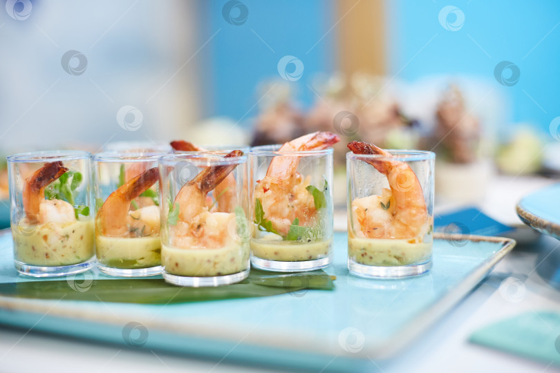 Скачать Вкусные закуски с креветками и сырным муссом в стеклянных стаканчиках на банкетном столе для фуршета. Деликатесы крупным планом, закуска, антипасти, блюдо из морепродуктов фотосток Ozero