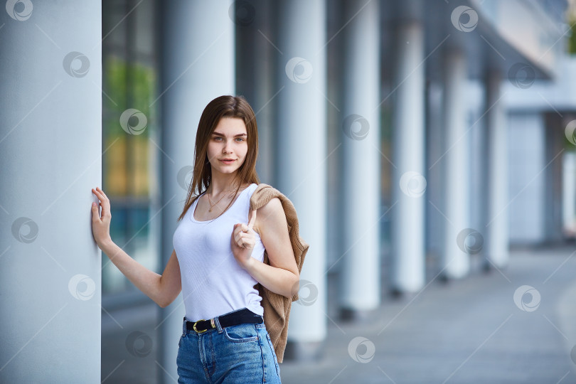 Скачать молодая девушка стоит возле здания и смотрит в кадр. фотосток Ozero