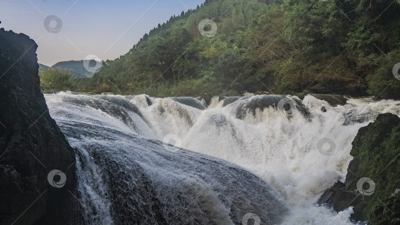 Скачать Необычный водопад. Потоки воды хаотично стекают по валунам, бурля и пенясь. фотосток Ozero