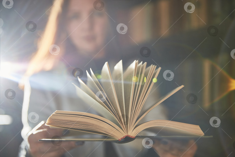 Скачать Молодая женщина держит открытую книгу. Небольшая глубина резкости. Сосредоточьтесь на книге. фотосток Ozero