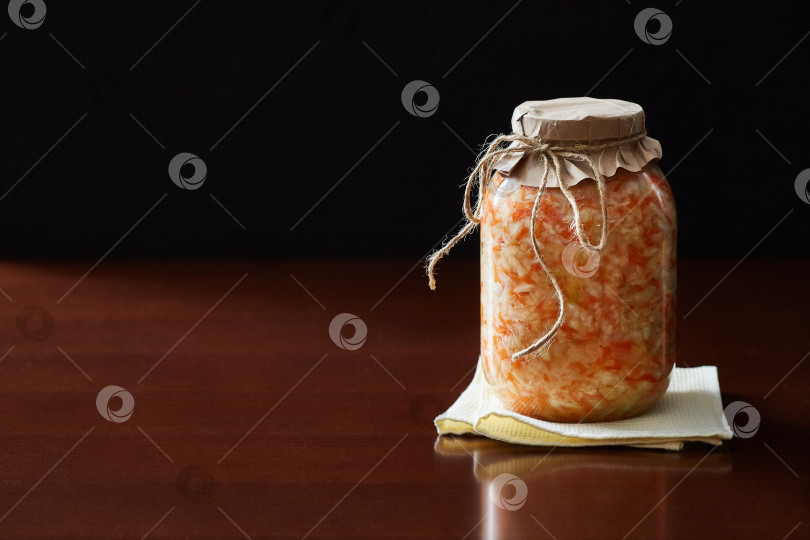 Скачать Стеклянная банка с салатом из маринованной капусты на столе на темном фоне. фотосток Ozero
