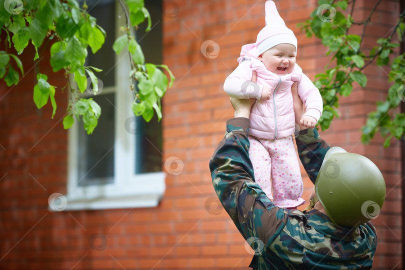 Скачать Отец-военный, пришедший с военных учений, весело подбрасывает малыша. фотосток Ozero