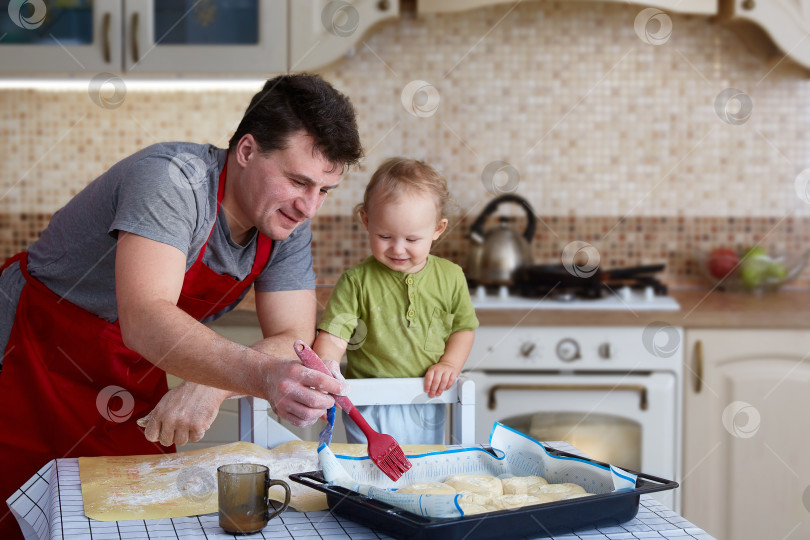 Скачать Отец и дочь пекут пироги, готовят еду и веселятся на кухне. Домашняя еда и маленький помощник. Счастливое родительство фотосток Ozero