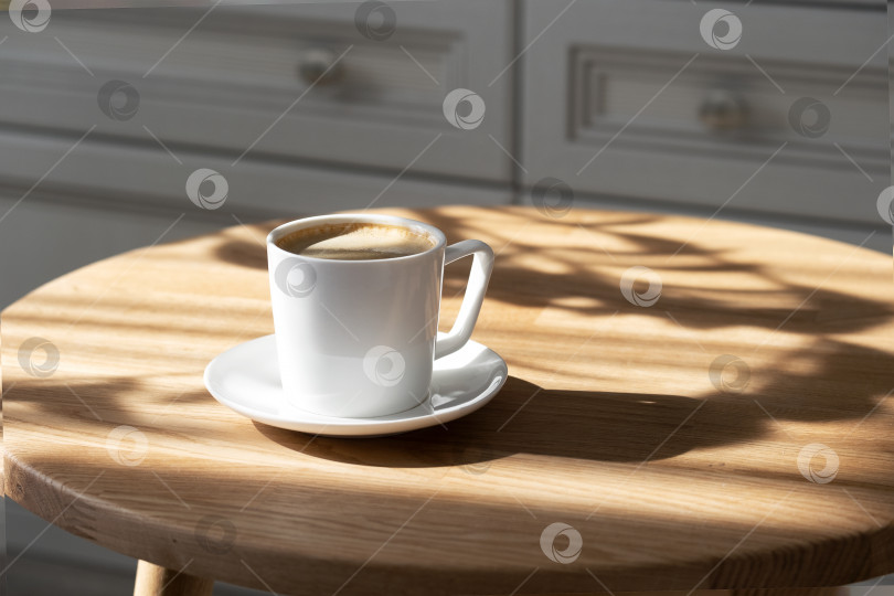 Скачать На круглом столе стоит белая фарфоровая чашка с кофе на блюдце фотосток Ozero