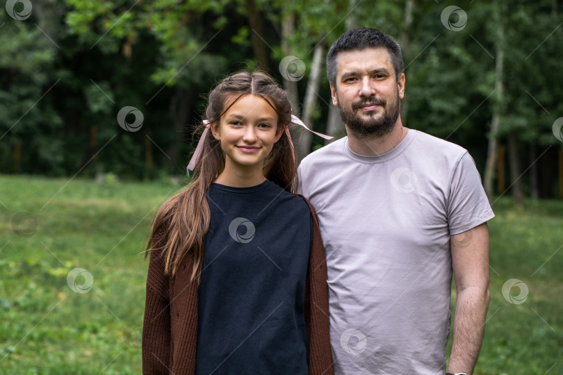 Скачать Отец средних лет и его дочь-подросток позируют в летнем парке фотосток Ozero