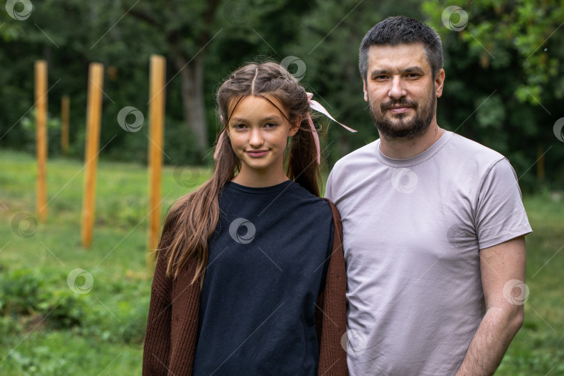 Скачать Отец средних лет и его дочь-подросток позируют в летнем парке фотосток Ozero