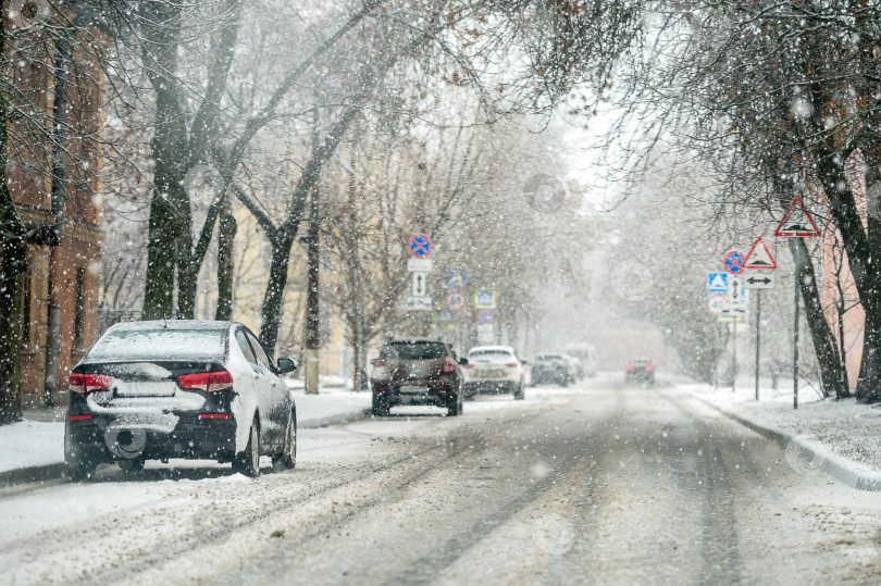 Скачать Автомобили, припаркованные на обочине дороги в городе во время зимнего снегопада фотосток Ozero