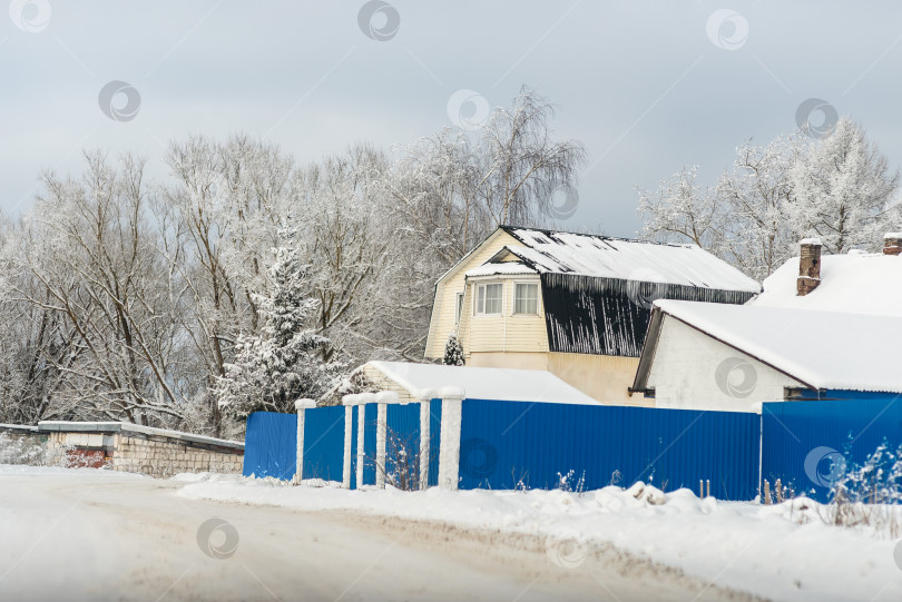 Скачать Зимний пейзаж - вид на деревенскую дорогу и дома в солнечный день фотосток Ozero